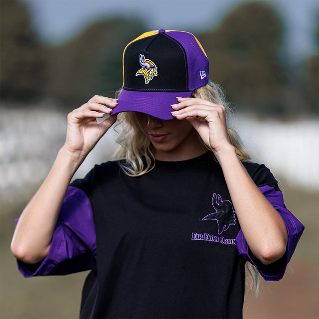 Model adjusting the Colour Block New Era Snapback in black and purple, close front view