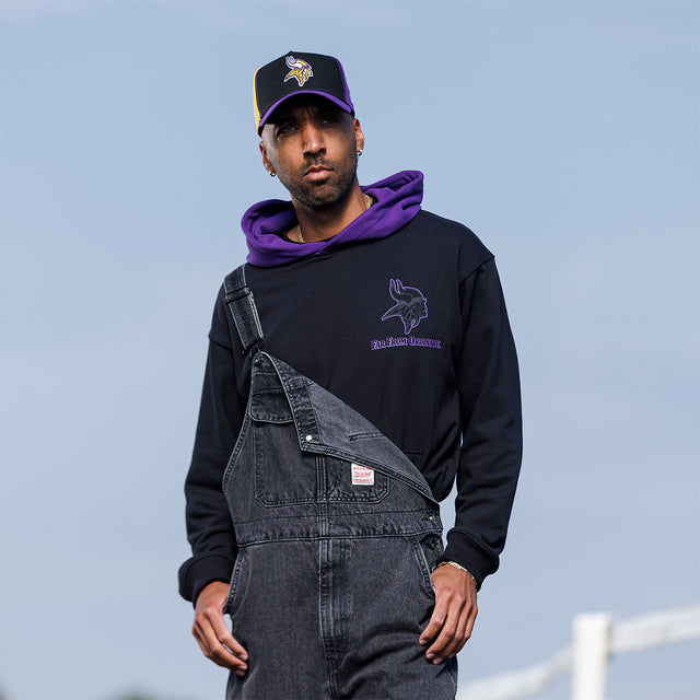 Model wearing the Two-Tone Hoodie in black and purple with a Vikings cap, front view