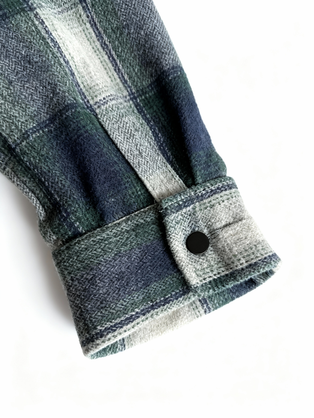Close-up of a plaid shirt sleeve with a button on a white background